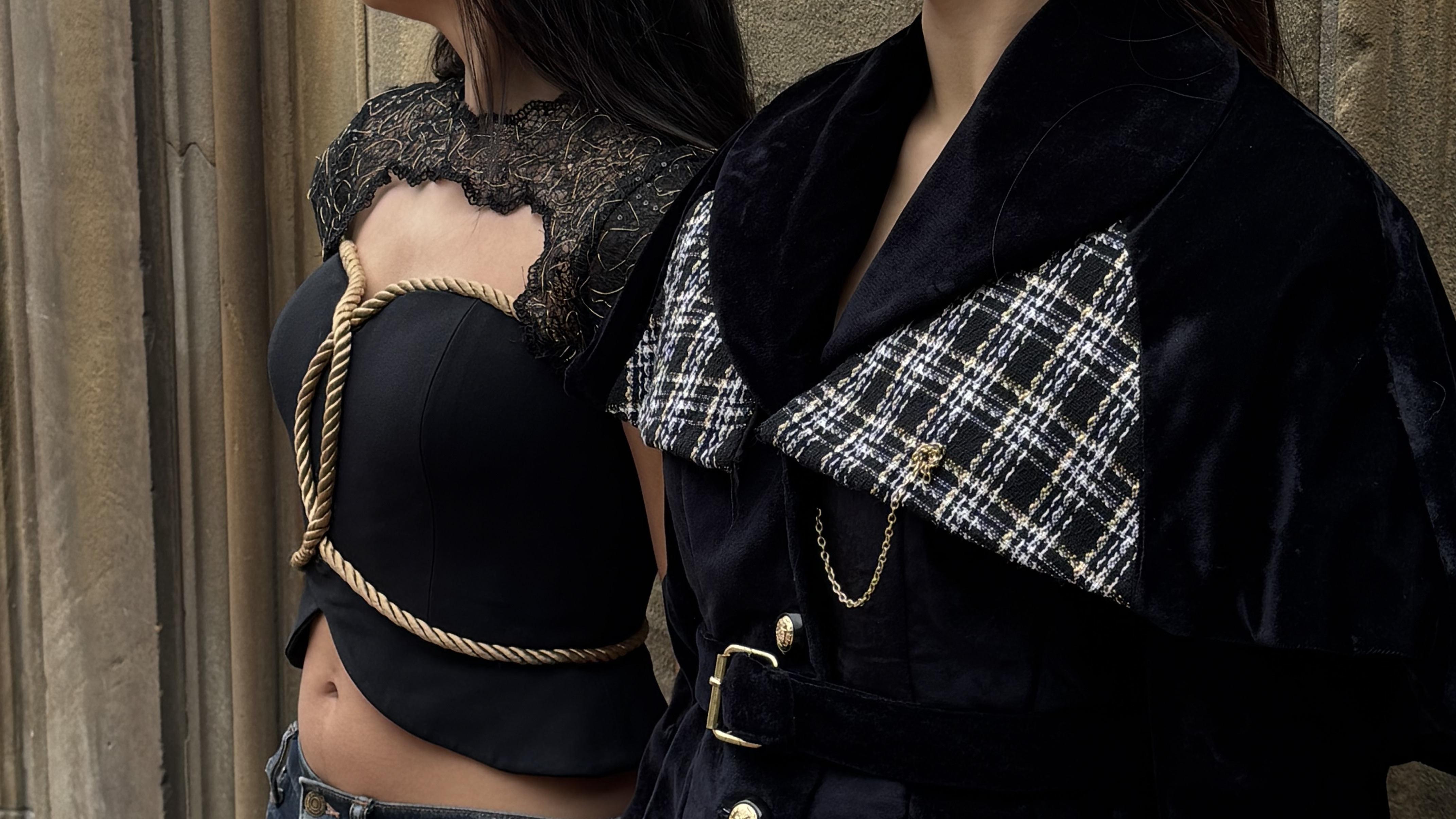 Two figures in profile wearing the Veste-Cape n° I, photographed against stone architecture